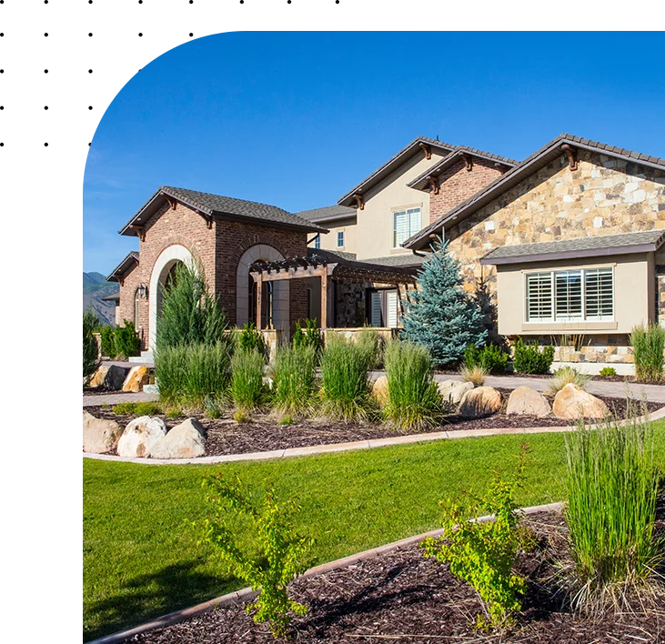 Stone house with landscaped yard and blue sky.